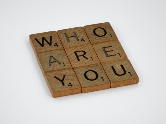 Brown wooden puzzle board with the word Who Are You.